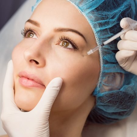Close-up of female patient receiving an injection on her face in clinic Close-up of female patient receiving an injection on her face in clinic